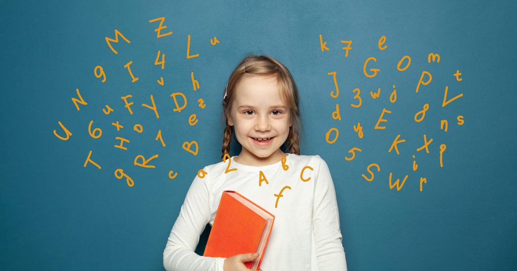 Iloinen tyttö kirja kädessä liitytaulun edessä.