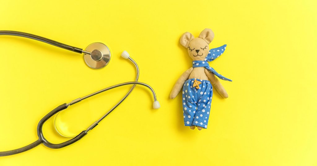 Keltaisella taustalla on pehmolelunalle, jonka vieressä stetoskooppi.